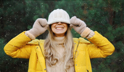 Winter portrait of happy cheerful woman having fun in hat against Christmas tree in forest