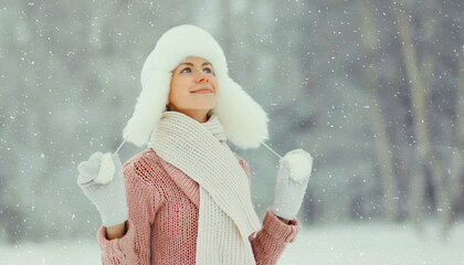 Happy smiling young woman in winter day, joyful girl in white hat, sweater enjoys warm weather
