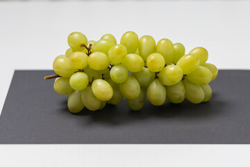 A studio shot from above of a bunch of light green grapes resting on a clean, matte black surface