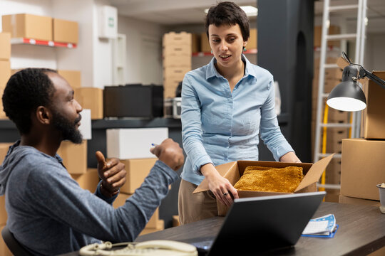 Two diverse coworkers organizing the shipment of products in a small business logistics center, exemplifying the manual and tech driven processes of modern retail logistics. Import export.