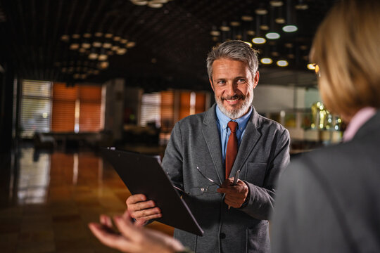 Mature businessman smiling with clipboard during a business meeting