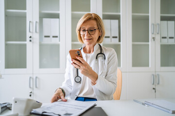 Mature female doctor using smart phone for healthcare consultation