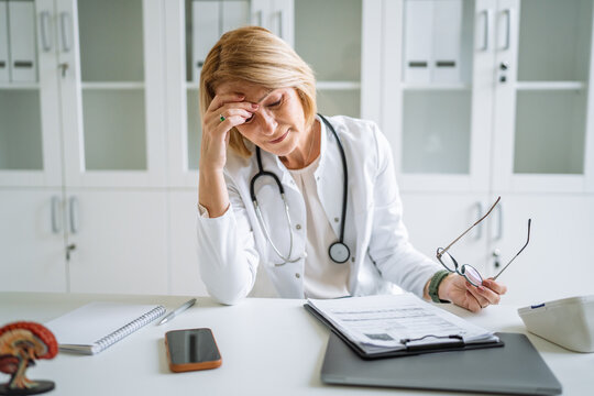 Stressed female doctor experiencing headache during office work