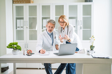 Medical team collaborating discussing patient data on laptop