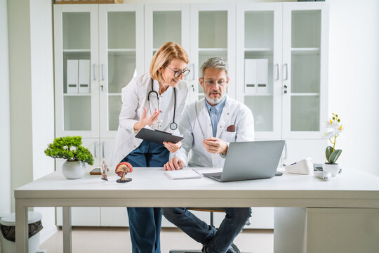 Doctors collaborating on laptop reviewing medical records