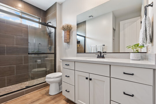 A bathroom that includes a toilet, sink, mirror, and a walkin shower - Powered by Adobe