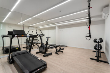 Bright gym features several types of workout machines including a treadmill, stationary bike, and...