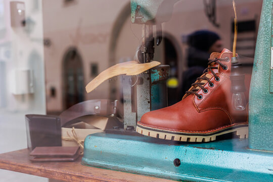 Close-up of a shoemaker s workshop display featuring a brown leather boot, vintage sewing machine, and leather accessories, reflecting craftsmanship and traditional cobbling techniques