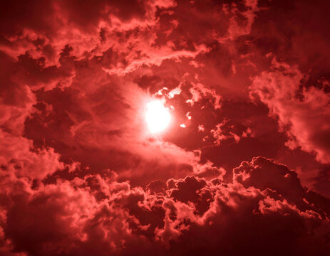 Dramatic red clouds surround a glowing sun, creating an intense and fiery sky. A powerful and atmospheric natural scene. - Powered by Adobe