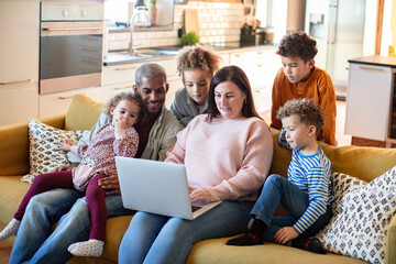 Adult parents and children happily watching laptop at home