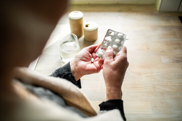 Senior adult taking pill at home, focused
