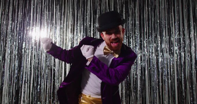 Dancing cute funny and extravagant man in shining glittering jacket, feels excited, moving, promotion celebrating success, amusement humorous guy, metallic shiny glitter long rain garland background