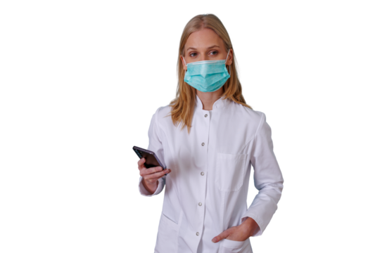 Healthcare worker, doctor or nurse, wearing a protective face mask and lab coat, holding a mobile phone. Background is transparent