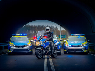 Policjant na motocyklu i policyjne radiowozy w tle. policyjna grupa speed