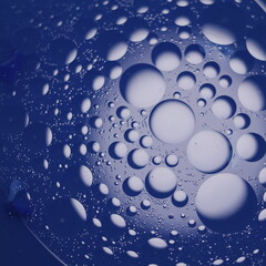 Una toma de cerca de un fondo abstracto de varias burbujas en agua y aceite en movimiento en un fondo de color azul oscuro  con algo de desenfoque
