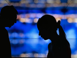 Silhouettes standing and looking down against city lights