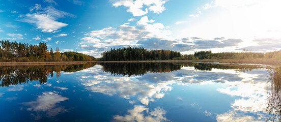 Colourful autumn landscape in the forest next to a lake during sunset, water reflections and colourful sky