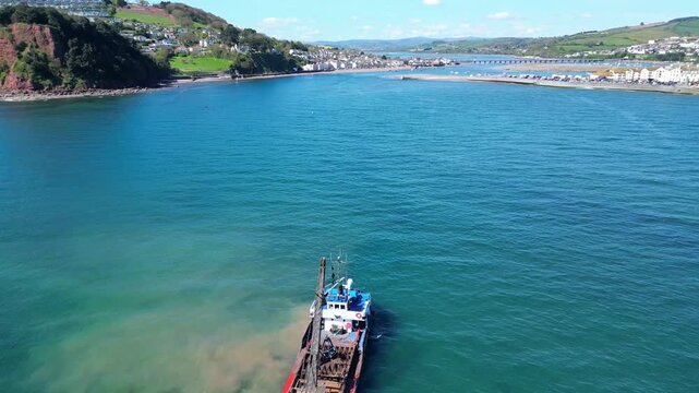 Teignmouth, South Devon, England: DRONE VIEWS: Silt being dredged by a dredger near the River Teign estuary to ensure the unhindered passage of shipping to the port of Teignmouth (Clip 1 of 3). 