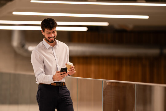 Young businessman smiling while checking smartphone on coffee break