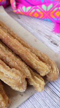 Vertical shot of churros on a table with chocolate on the side. Mexican food
