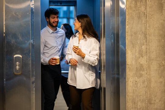 Business colleagues exiting elevator enjoying coffee break