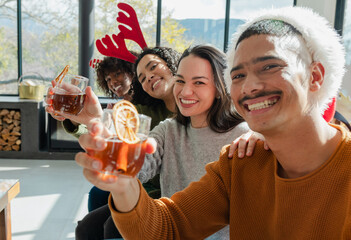Diverse friends clinking glasses while wearing festive headwear on couch in living room, copy space
