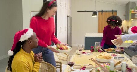 Diverse friends at home hearing dinner bell ringing carrying dishes arranging on table as laughing - Powered by Adobe