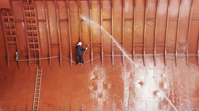 rew cleaning bulk carrier hold after discharging petroleum coke using seawater, chemicals, and brushes. dangerous job 50