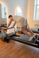 Dynamic reformer plank, individual executes dynamic plank with tension on reformer for endurance