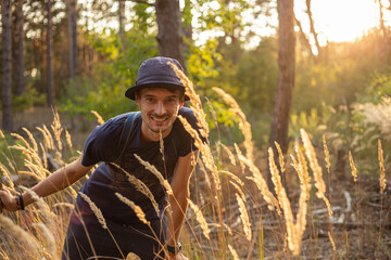 Handsome young caucasian man in the forest woods with shining spikelets in black panama