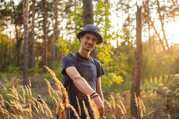 Handsome young caucasian man in the forest woods with shining spikelets in black panama
