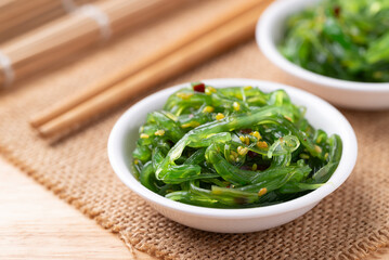 Wakame seaweed salad with sesame seed in a bowl with chopsticks