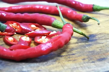 The fresh curly red chilies or capsicum annuum on an old wooden cutting board