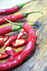 The fresh curly red chilies or capsicum annuum on an old wooden cutting board