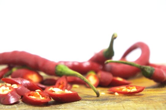 The fresh curly red chilies or capsicum annuum on an old wooden cutting board