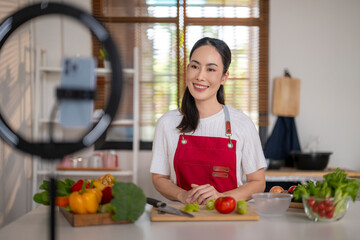 Asian woman vlogging about healthy cooking in kitchen