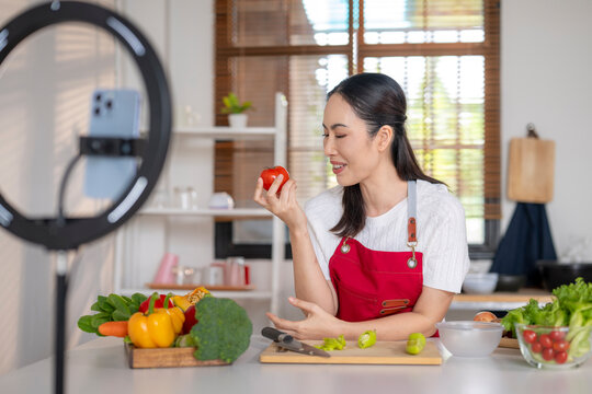 Woman vlogging cooking healthy vegetables in home kitchen