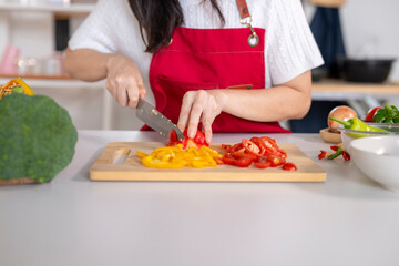 Woman preparing healthy meal chopping colorful bell pepper vegetables