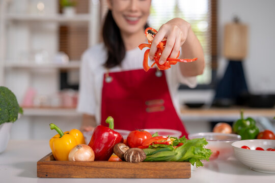 Woman adding chopped bell pepper to healthy salad