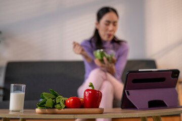 Woman eating healthy salad using tablet for nutrition