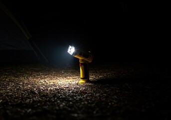 Powerful handheld electric light casting a bright beam across the dark ground at a campsite, essential gear for nighttime exploring and safety ,travel ,exploration ,device