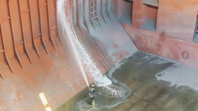 rew cleaning bulk carrier hold after discharging petroleum coke using seawater, chemicals, and brushes. 31