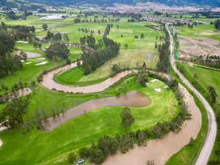 High aerial drone view capturing the broad meanders of the muddy Río Bogotá cutting through a...