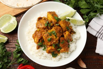 Chicken tikka masala with rice served on wooden table, flat lay