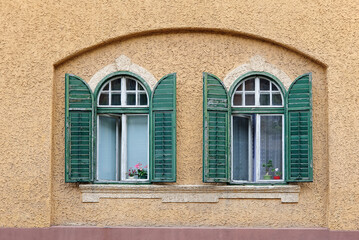 Two windows with wooden green shutters in niche