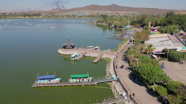 Aerial shot advancing along the malecon in Cajititlan showing boats, lakefront path and green areas