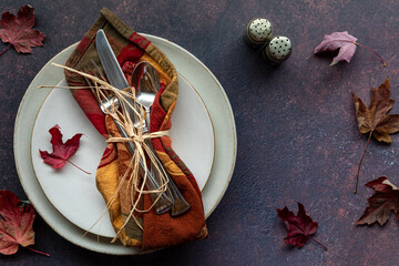 Top down view of a fall inspired table place setting against a dark background.