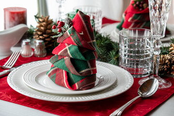 A beautifully folded red and green napkin on a table place setting.
