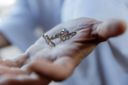 A bright close-up of a hand holding elegant silver cufflinks shaped like a treble clef &mdash; a refined accessory symbolizing music, creativity, and timeless sophistication.