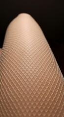 Close-up of a leg wearing textured stockings, showcasing intricate diamond pattern against skin.